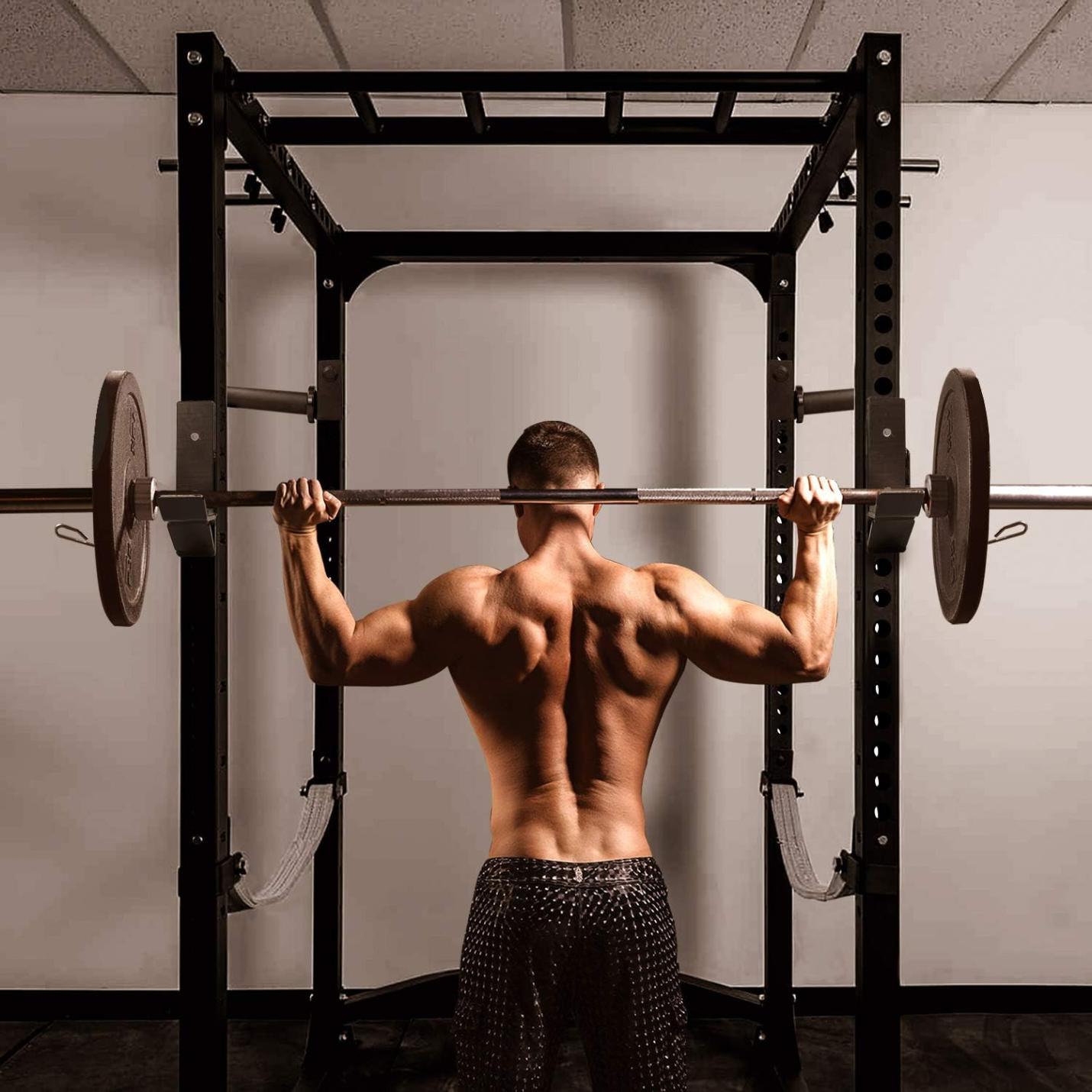 Een gespierde man bereidt zich voor om een halter op te tillen op een veilige en betrouwbare J-haken voor je power rack in een sportschool.