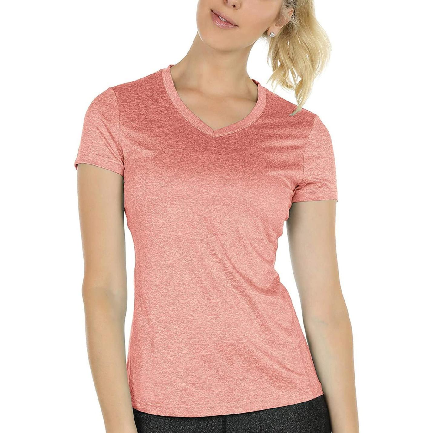 Zin met vervangen productnaam: Vrouw in een roze Ervaar optimaal comfort en stijl met ons dames sportshirt met V-hals poserend tegen een witte achtergrond.