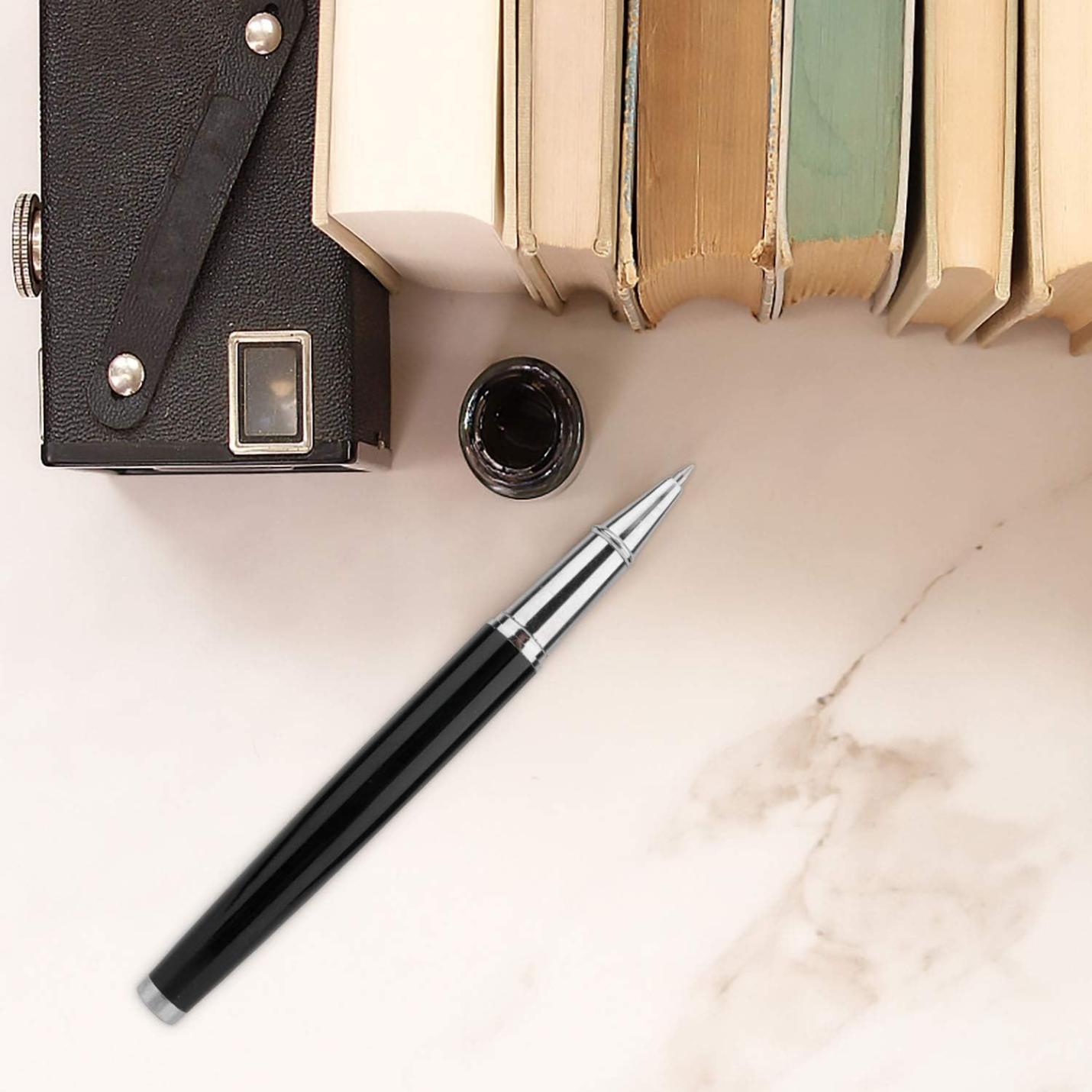 Een zwarte rollerbalpen ligt naast een inktpot en een stapel hardcover boeken, met een leren tas op een marmeren oppervlak. Laat een blijvende indruk achter met deze elegante en hoogwaardige rollerbalpen.