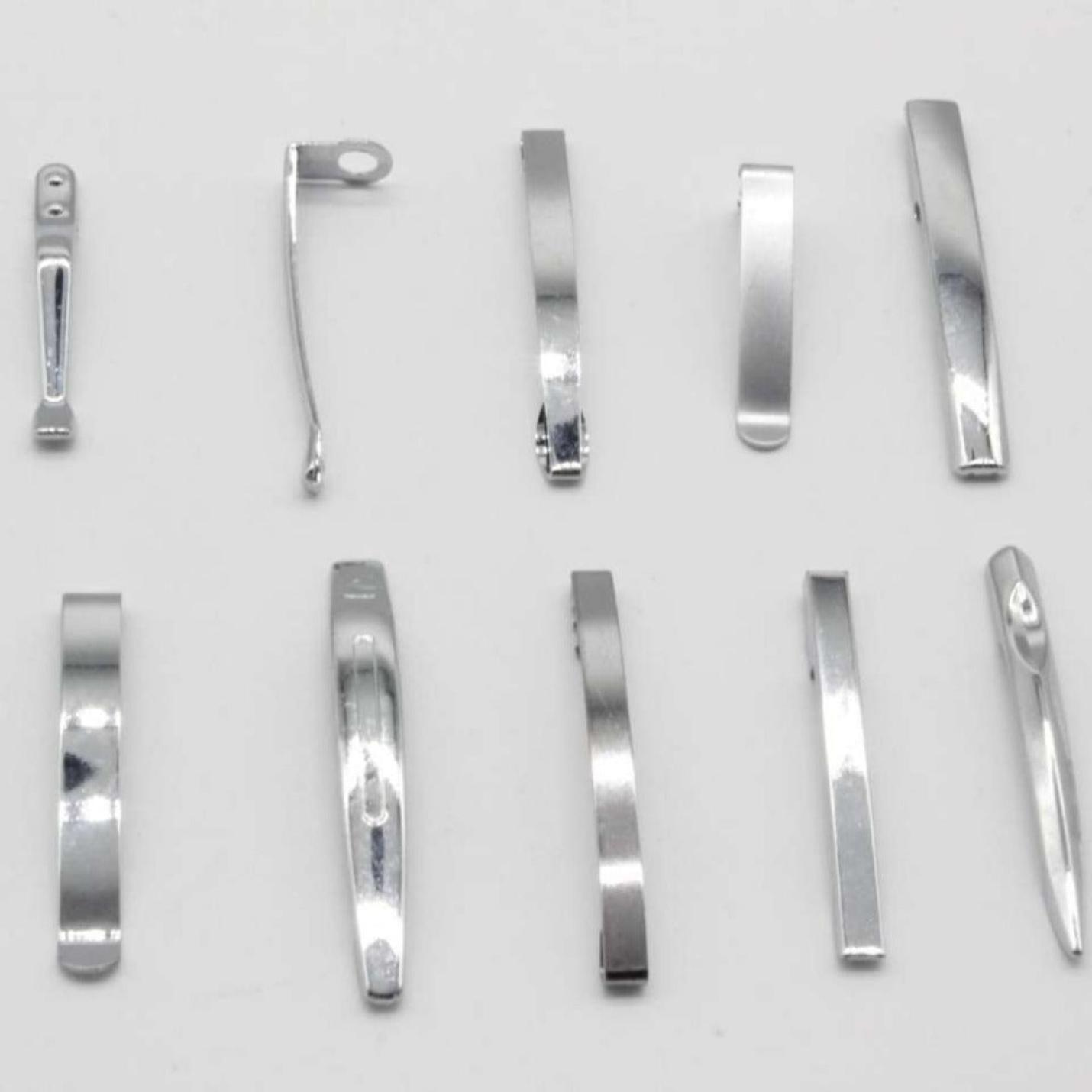 Een assortiment metalen nagelknippers en onderdelen, waaronder Nooit meer uw pen kwijtraken met deze set van 10 metalen penclips, neergelegd op een grijze achtergrond.