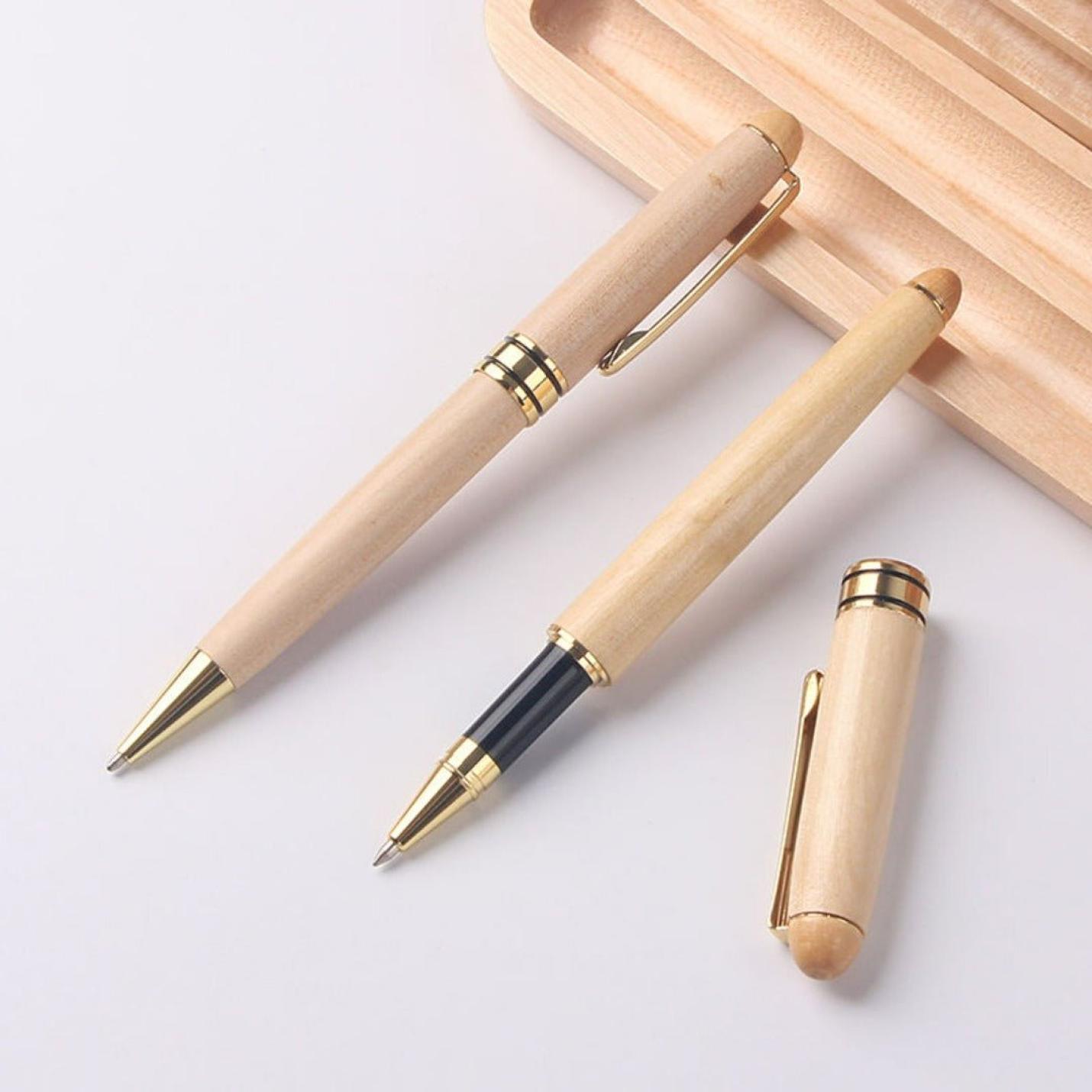 Ontdek de elegantie van onze hoogwaardige houten balpennen met gouden accenten op een lichte ondergrond.