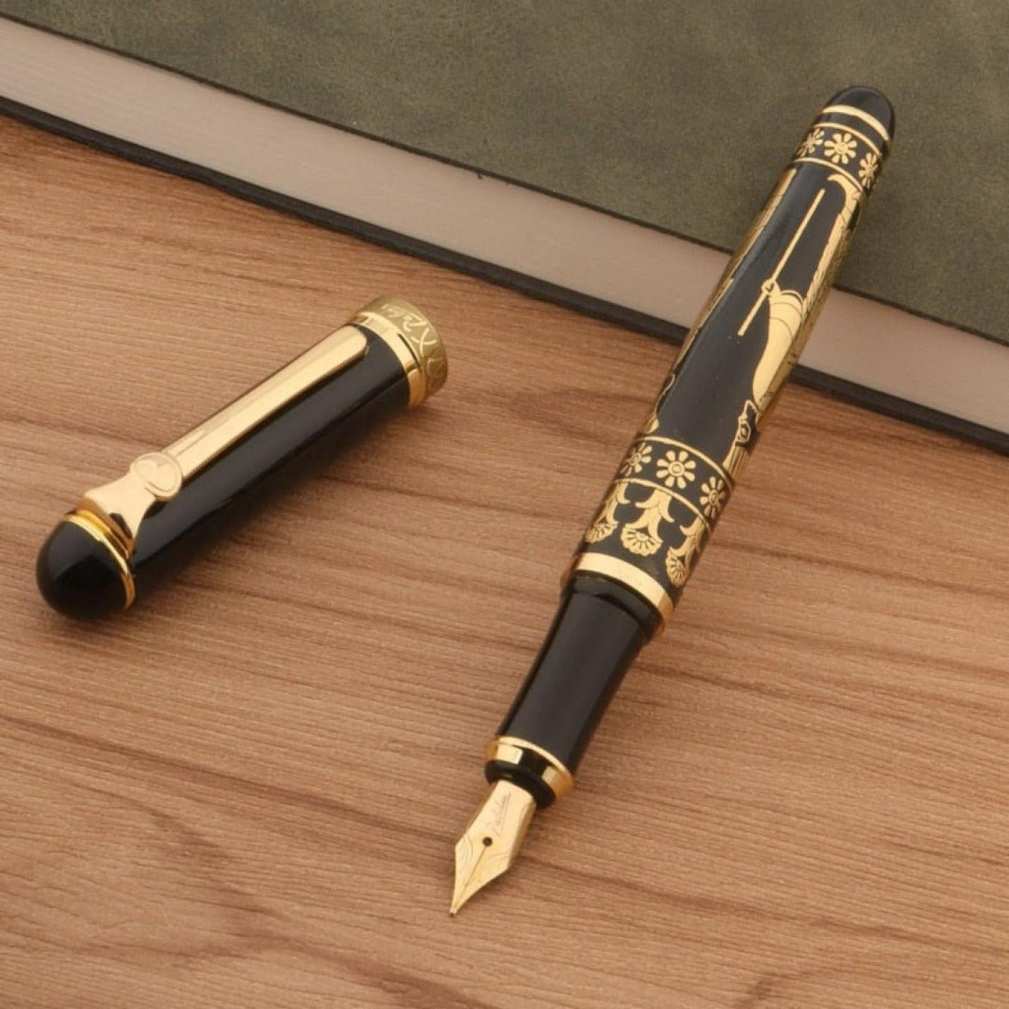 Schrijf geschiedenis met de Egyptische Farao vulpen, een zwarte en Egyptische gouden Farao vulpen, met zijn dop verwijderd liggend op een houten oppervlakte.