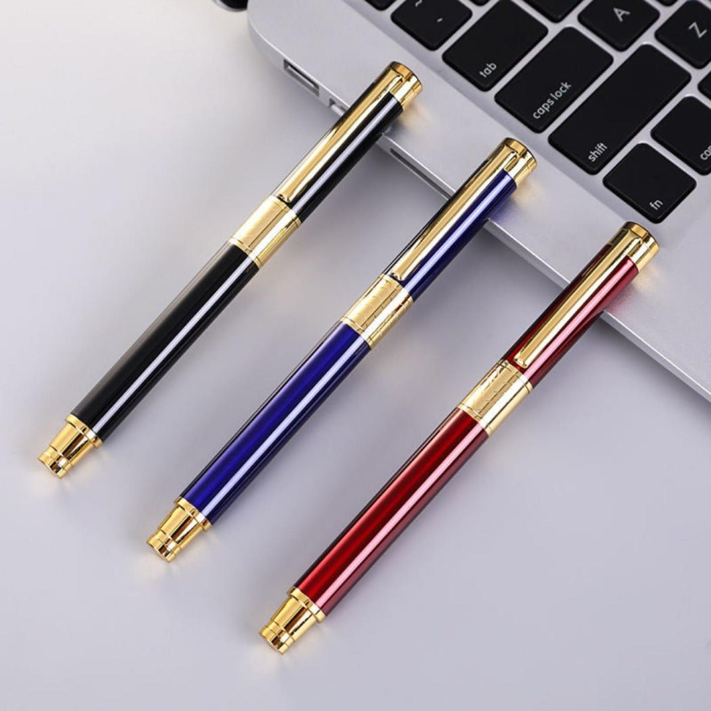 Drie elegante vulpennen in de kleuren zwart, blauw en rood met gouden accenten en een Schrijf in stijl met onze luxe marmeren vulpen-design, diagonaal op een laptoptoetsenbord geplaatst.