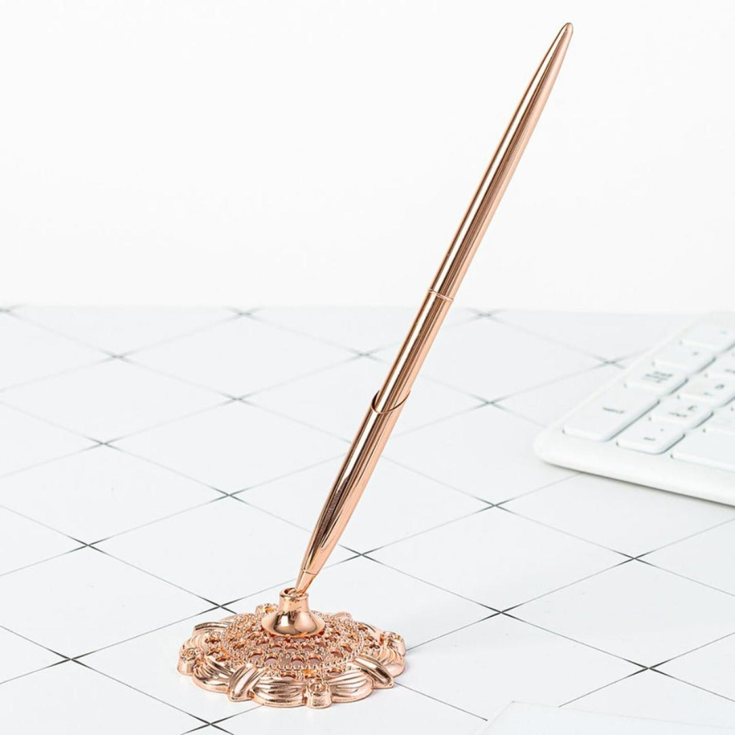 Schrijf met stijl en professionaliteit met deze elegante roségouden zakelijke metalen balpen die in de houder op een wit bureau met rasterpatroon staat naast een wit toetsenbord.