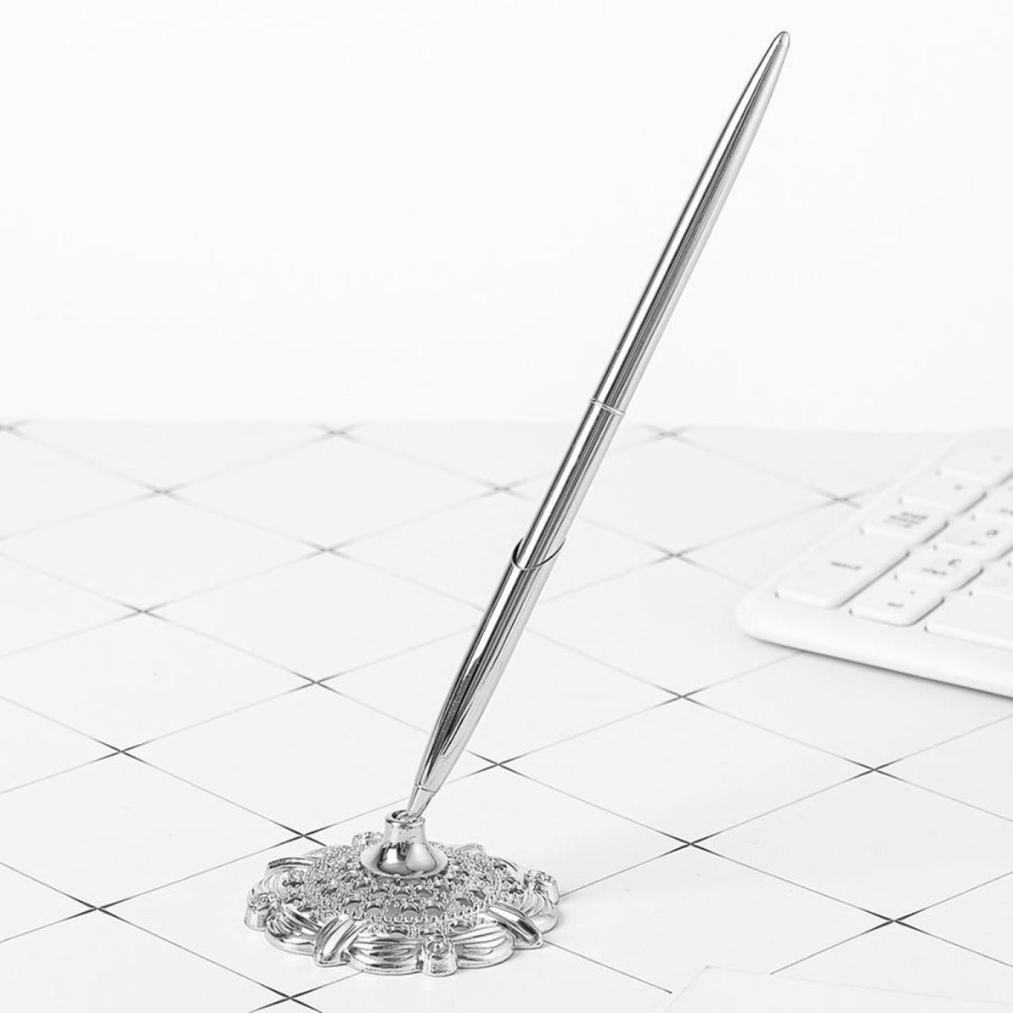 Een zilveren, elegante Schrijf met stijl en professionaliteit met deze elegante zakelijke metalen balpen rustend op een sierlijke houder met een wit toetsenbord op de achtergrond.