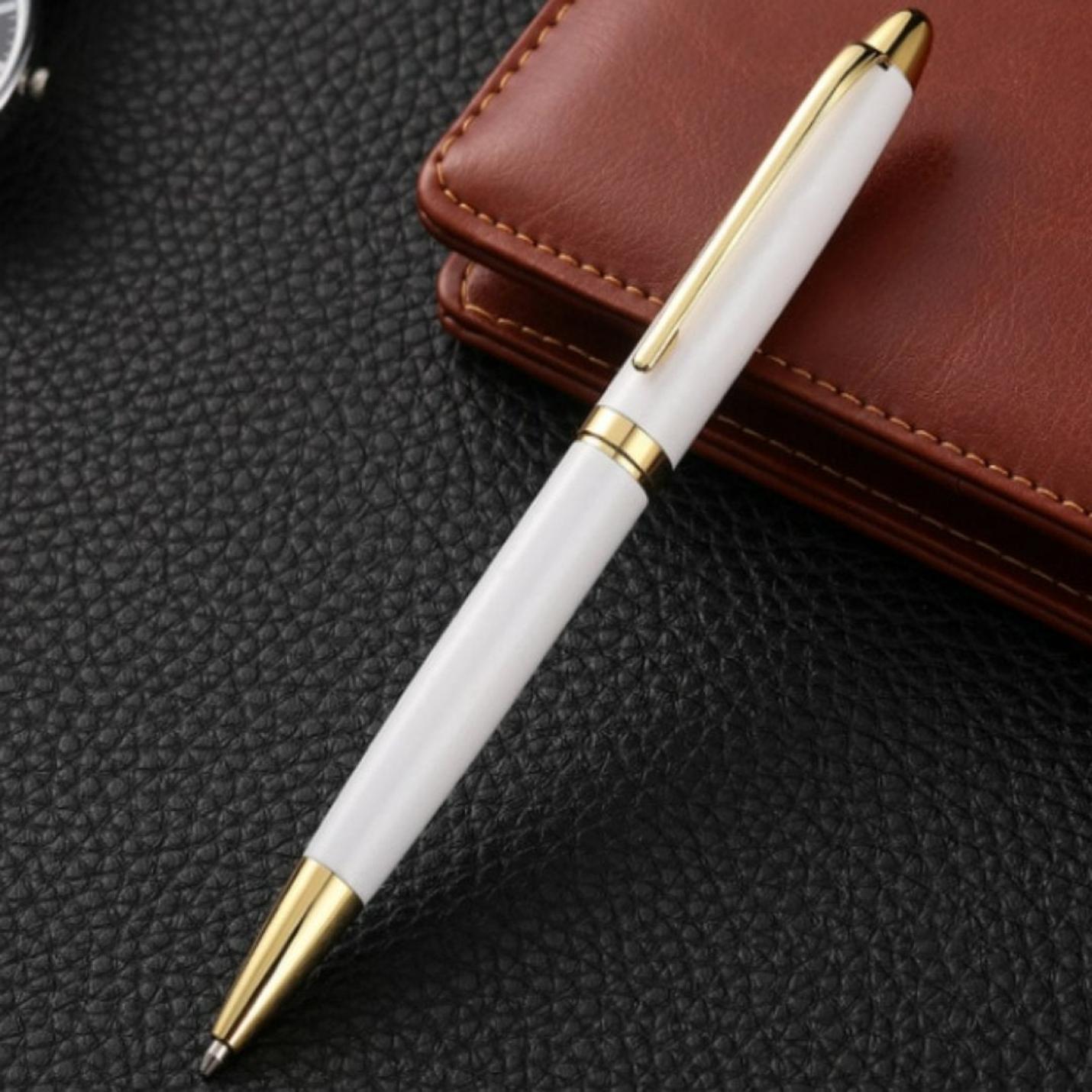 Zin met productnaam: Upgrade uw schrijfervaring met de luxe metalen balpen, die wit en goudkleurig is, rustend op een ondergrond zwart oppervlak naast een bruine leren portemonnee of hoes.