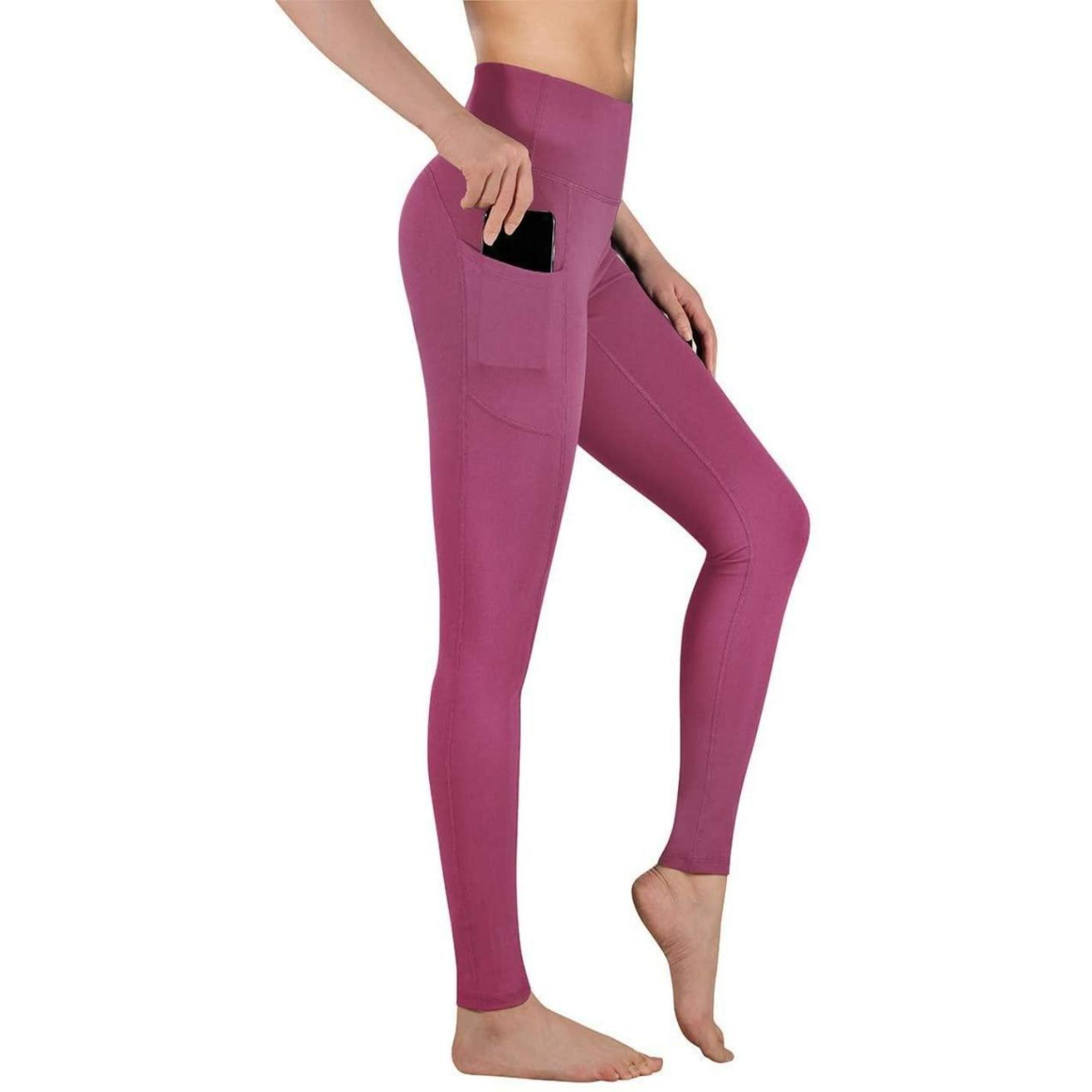 Vrouw, gekleed in roze hoge taille legging dames met een zijzak, staande op één been, wat de pasvorm en het ontwerp van de legging laat zien.