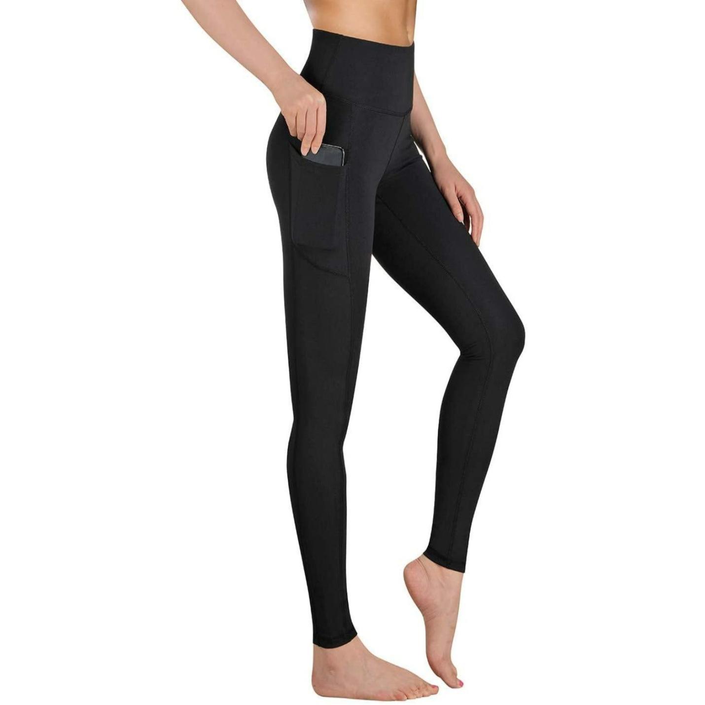 Staande vrouw in Hoge taille legging dames - Comfortabele, ondoorzichtige sportlegging voor sport en fitness met een zijzak, gericht op de zak en beenpasvorm, tegen een effen achtergrond.