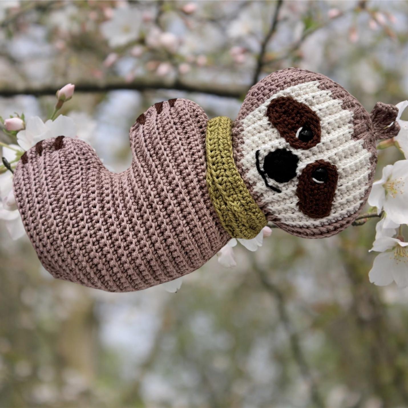Gehaakte knuffel Ribblz luiaard taupe met groene sjaal voorkant hangend aan en boomtak