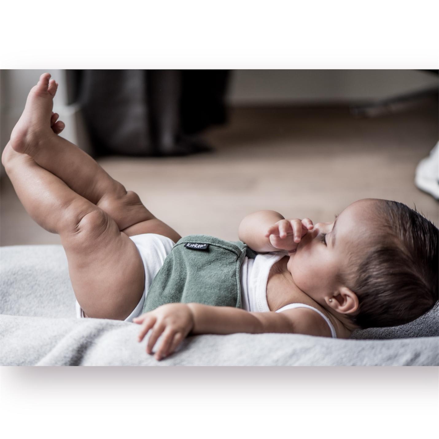 KipKep-woller- Calming Green-op buikje baby ligt met beentjes in de lucht