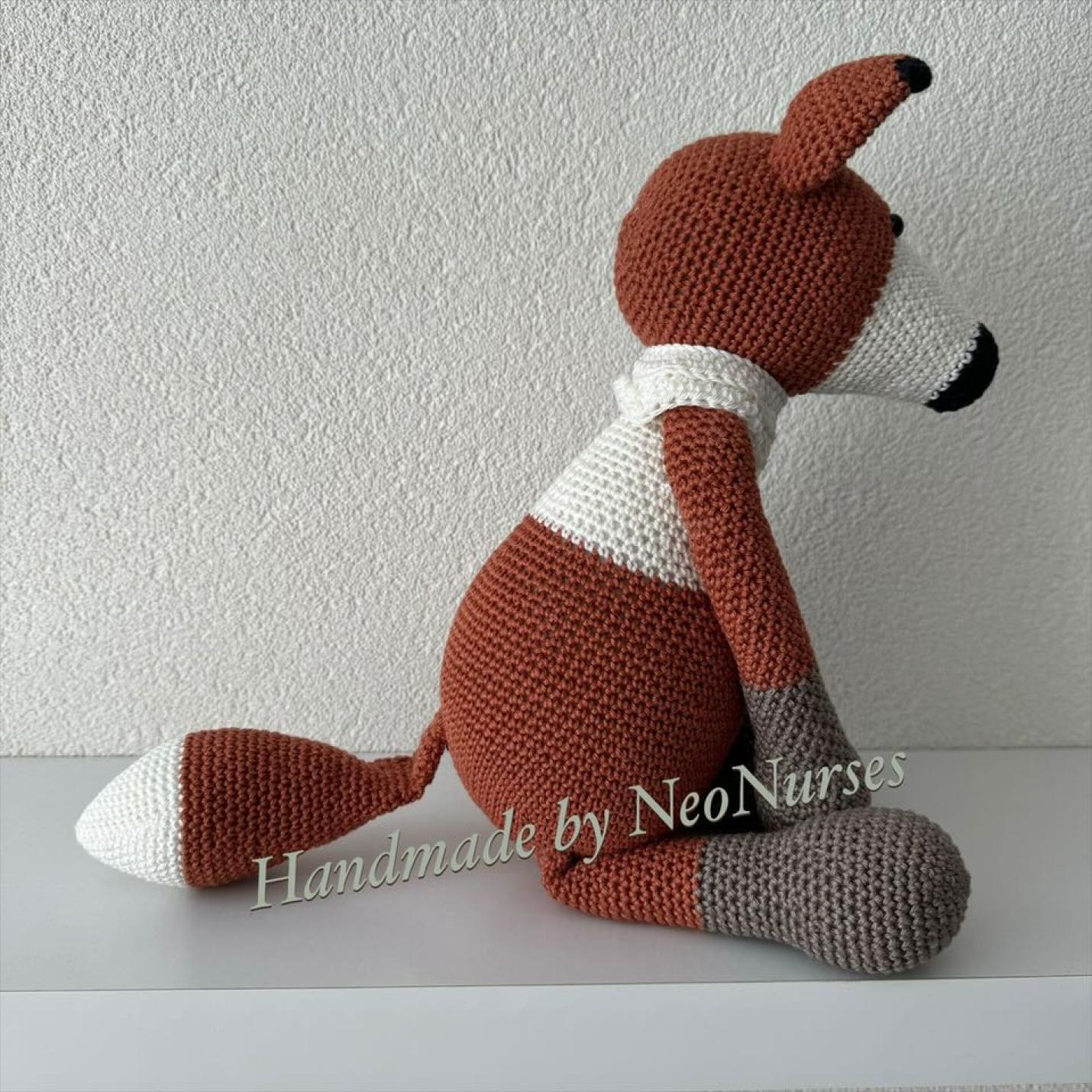 Zijaanzicht gehaakte knuffel Vos Floris Roest is gehaakte vos bruin met taupe voeten en armen, ecru sjaal om en ecru op borst en rond neus