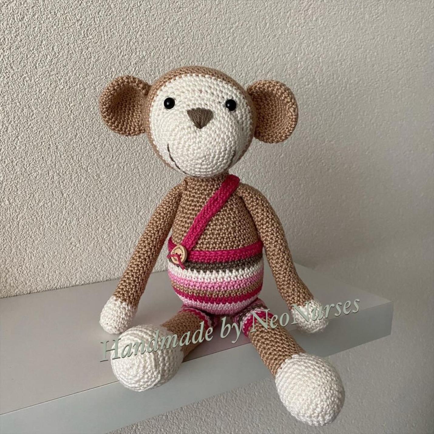 Aap Bengel Beige is gehaakte beige aap met ecruvoeten, handen en gezicht, met gestreept tuinbroek kleur roze, fuchsia, bruin en ecru