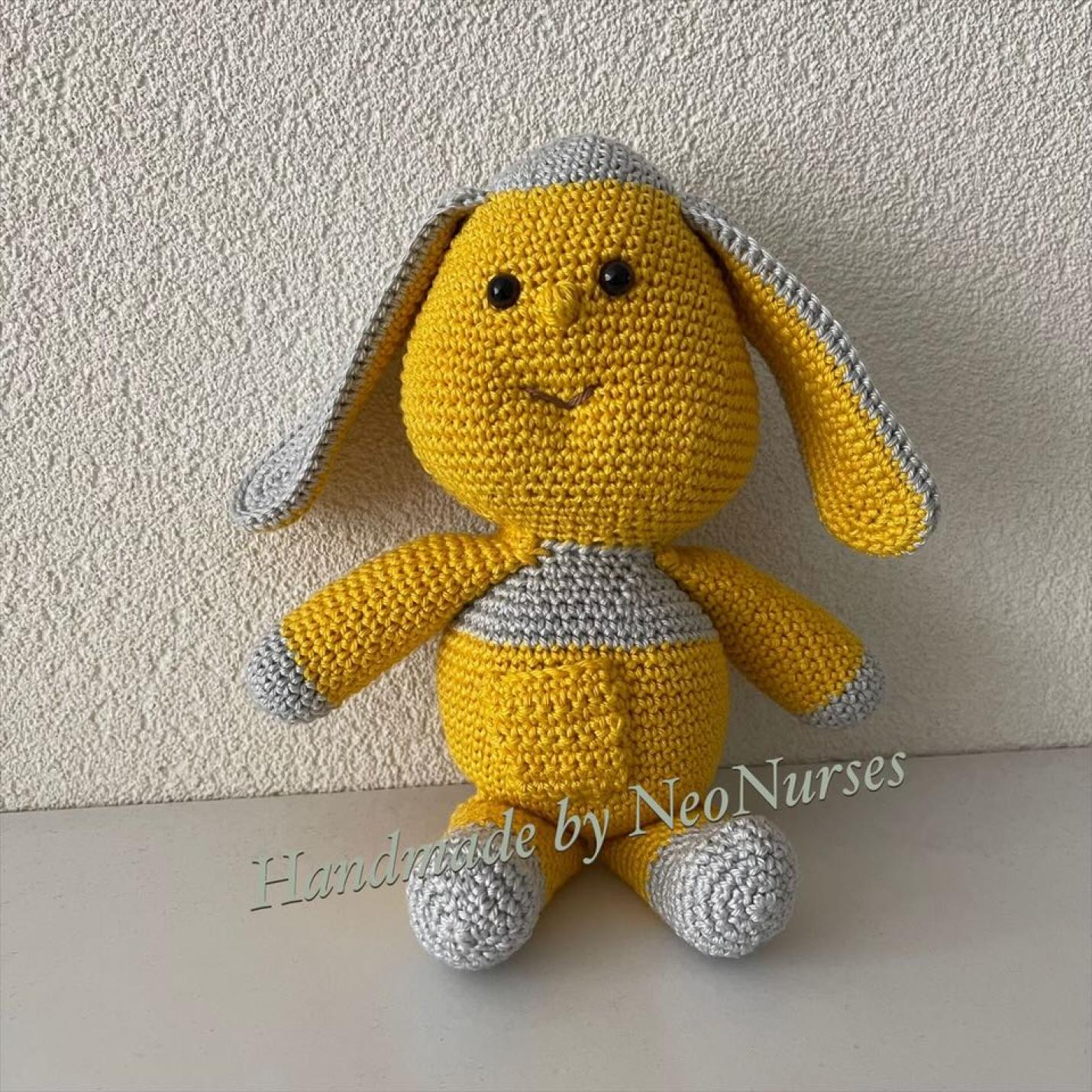 Dropje Okergeel is gehaakt knuffeltje met bolle buik okergeel, en peer hoofd erop, lange grijze oren en grijze voeten en handen