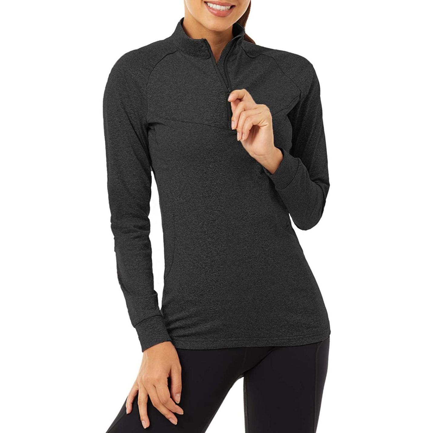 Vrouw in een Ervaar ultiem comfort en stijl met ons hardloopshirt voor dames met een halslijn met 1/4 rits, poserend met haar hand op haar heup.