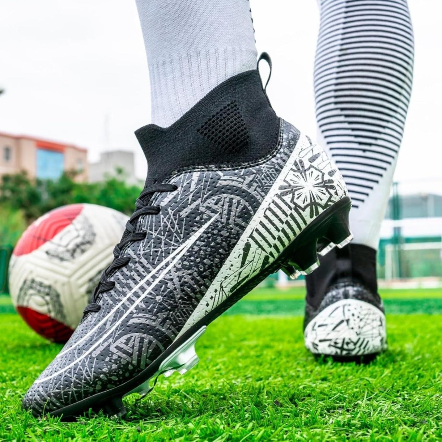 Close-up van iemand die de "Domineer het veld" high performance voetbalschoenen draagt op gras voor grip en stabiliteit, met een voetbal in de buurt.